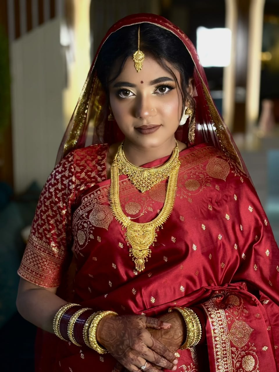 A bride in red silk and gold, mehendi on her hands