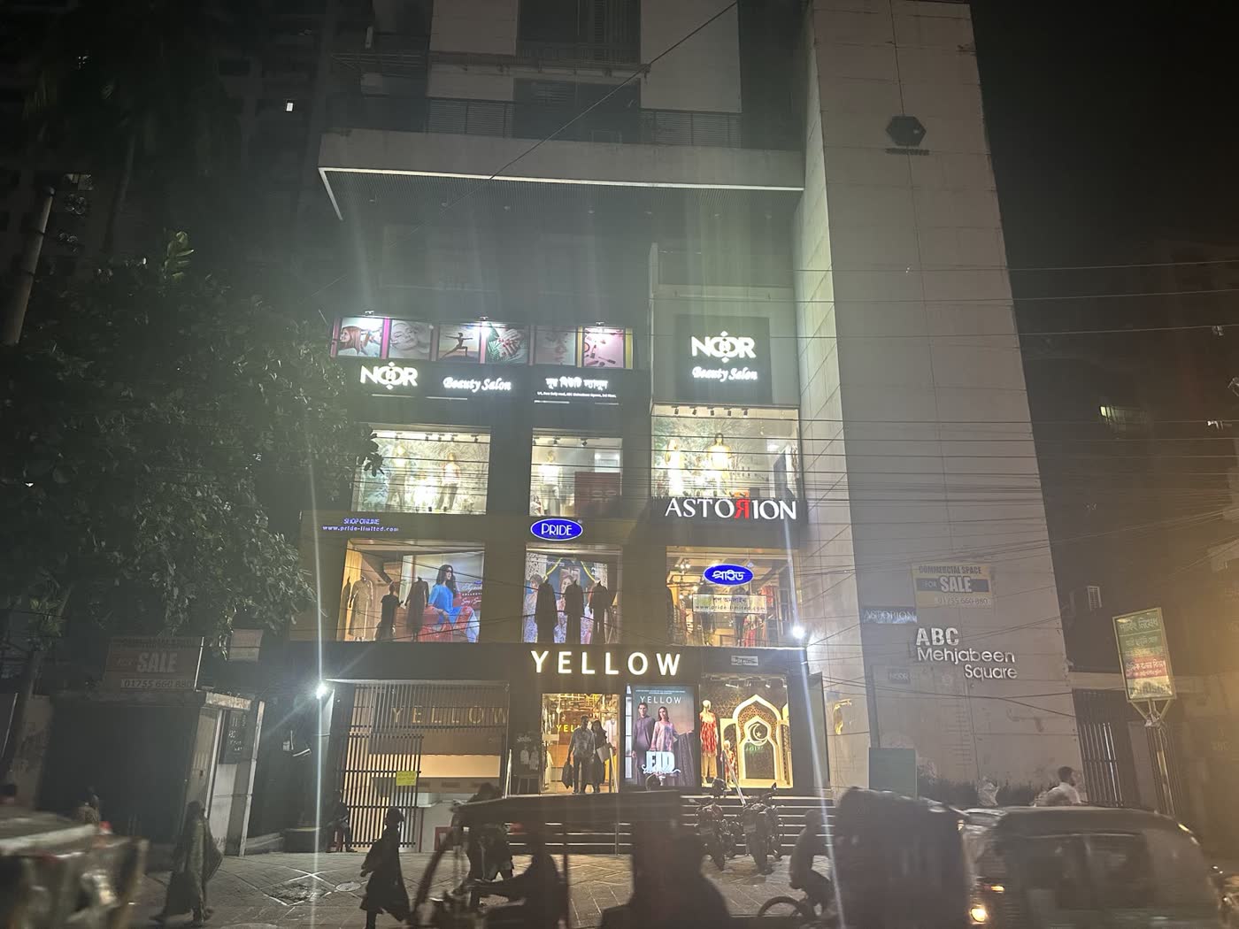The Noor Beauty Salon sign lit at night on the building's third floor